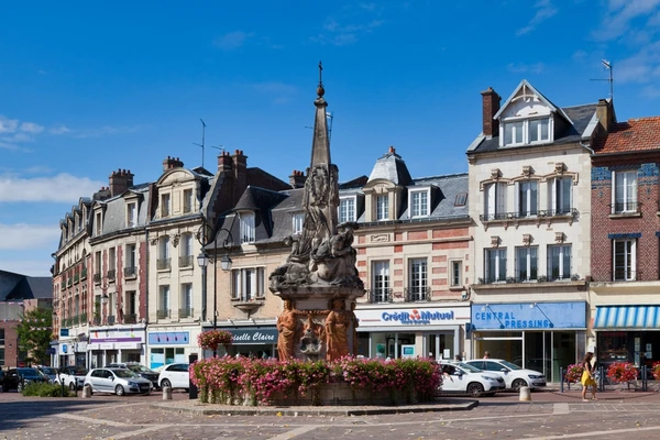 Photographie aérienne ou vue générale du paysage rural et urbain autour de Noyon (Oise), montrant des champs de cultures, quelques bâtiments industriels ou agricoles dispersés, et la silhouette lointaine de la ville. L'image doit transmettre l'environnement professionnel régional où intervient l'entreprise de génie civil, sans personnages ni éléments distrayants.