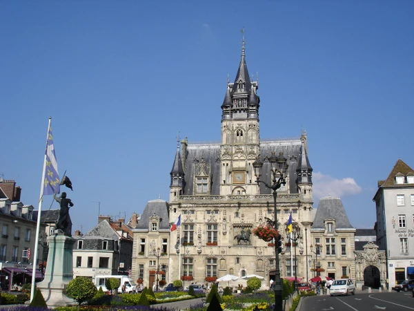 Vue aérienne ou paysage urbain-rural de Compiègne montrant le tissu urbain avec immeubles, routes et infrastructures, complété par des zones agricoles et industrielles environnantes. L'image doit transmettre l'environnement régional professionnel où intervient l'entreprise de génie civil, illustrant clairement Compiègne comme zone d'intervention, sans personnages ni éléments distrayants.